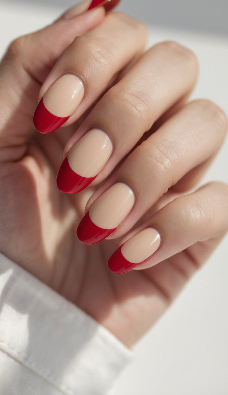A creamy nude base with glossy red French tips