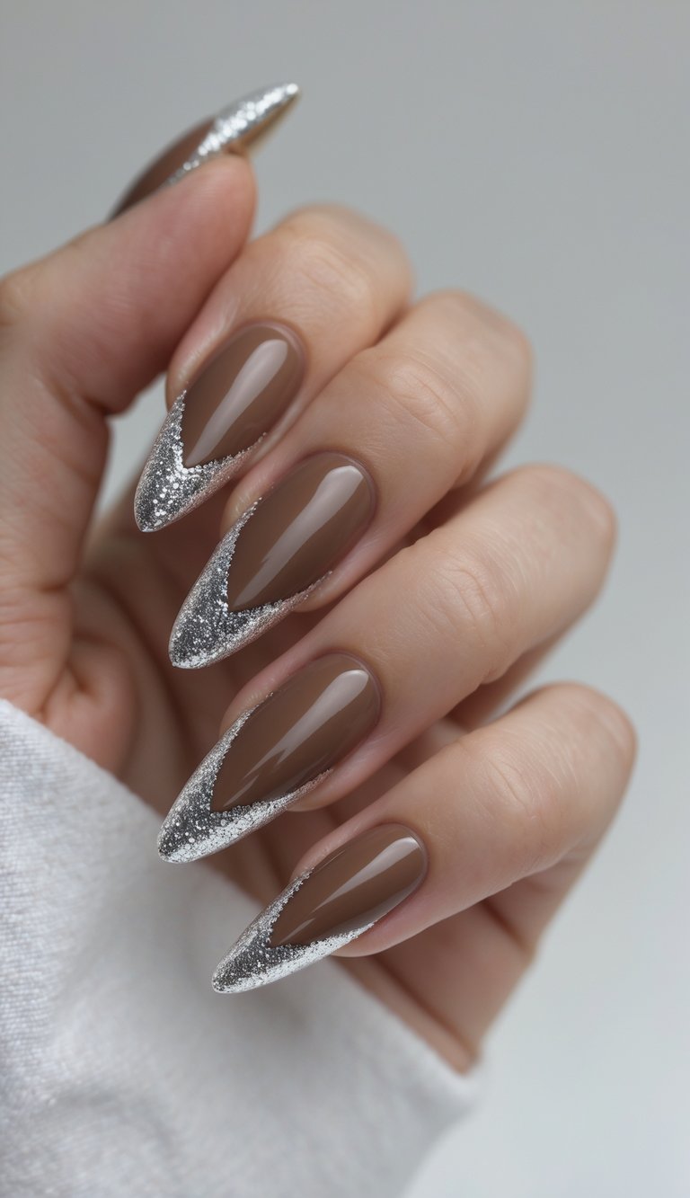 Close-up of one hand with mocha-colored nails and glittery French tips against a white background.