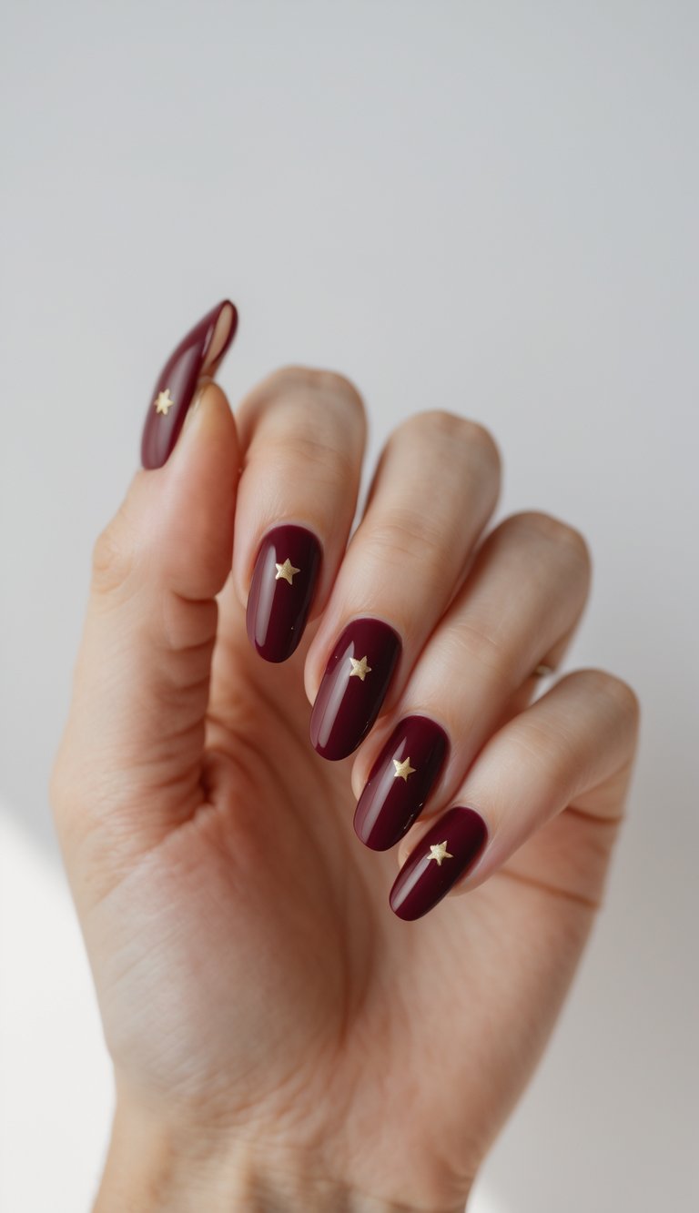 Close-up of one hand with deep red nails decorated with small gold stars against a white background.