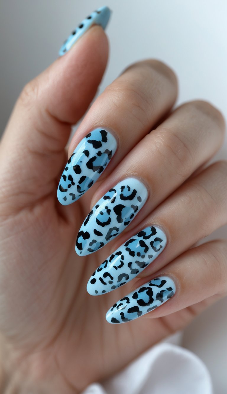 Close-up of one hand showing nails painted with light blue leopard print design against a white background.