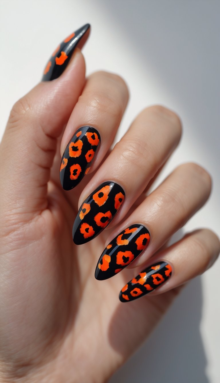 Close-up of one hand with black nails decorated with red and orange leopard spots against a white background.