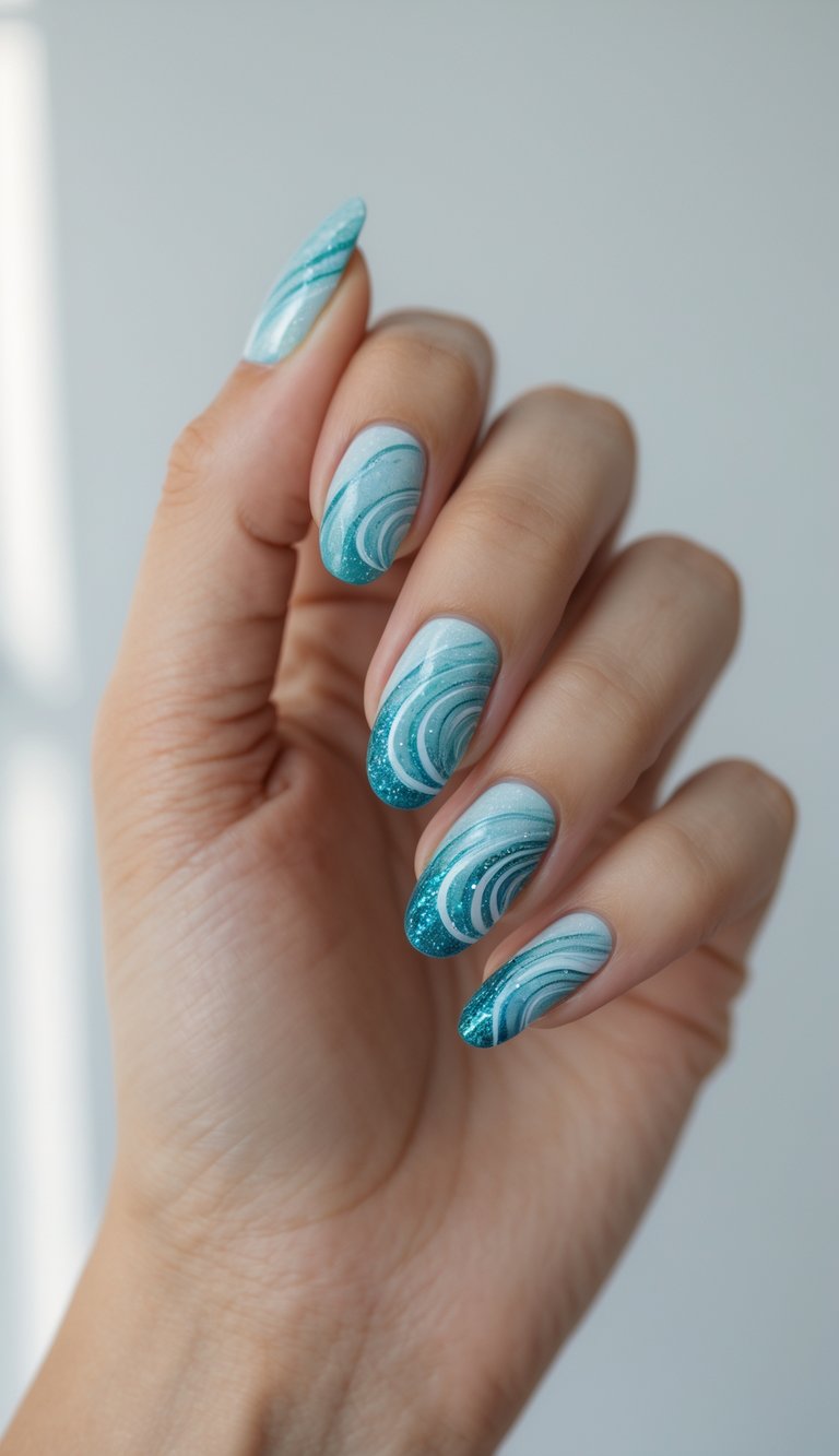Close-up of a single hand with nails painted in blue and turquoise swirl patterns with glitter, against a white background.