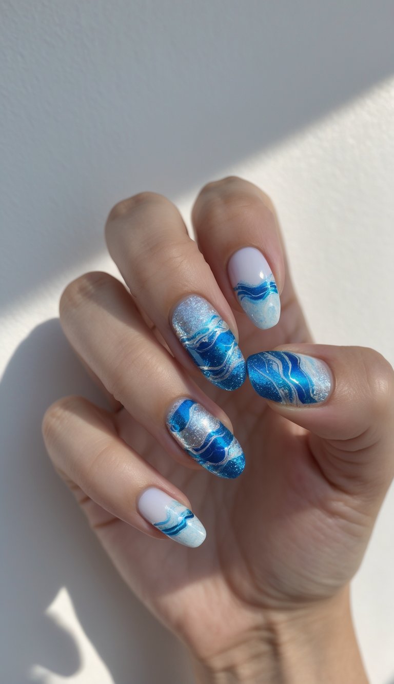 Close-up of one hand with blue and silver foil coastal nail art against a white background.