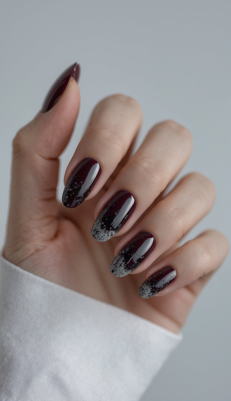 Close-up of one hand showing dark red nails with black speckled nail art on a white background.