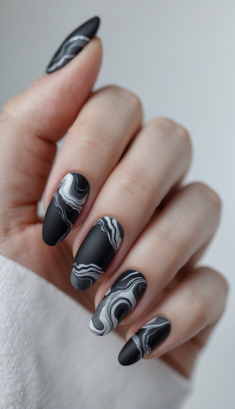 Close-up of one hand showing nails with matte black marble design against a white background.