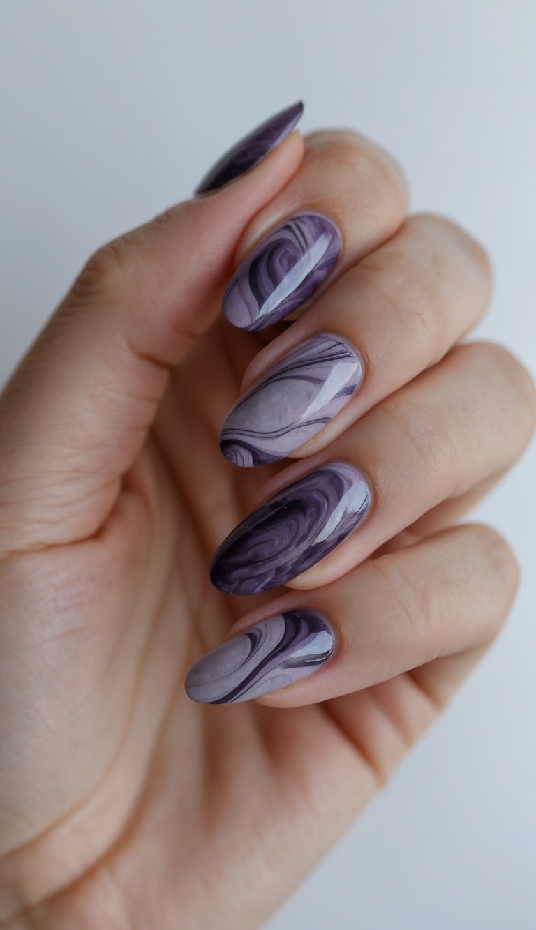 Close-up of one hand with marbled plum and slate colored nails against a white background.