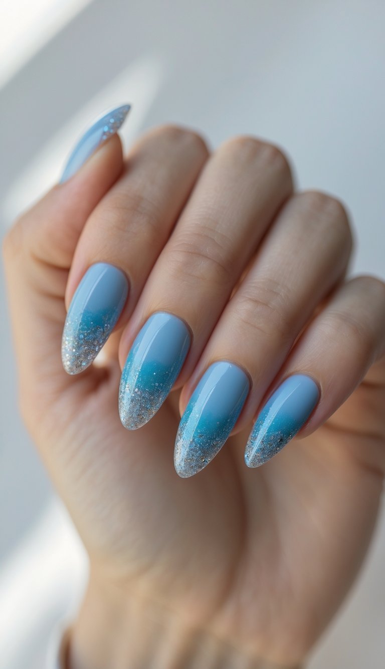 Close-up of one hand with blue gradient nails and glitter tips against a white background.