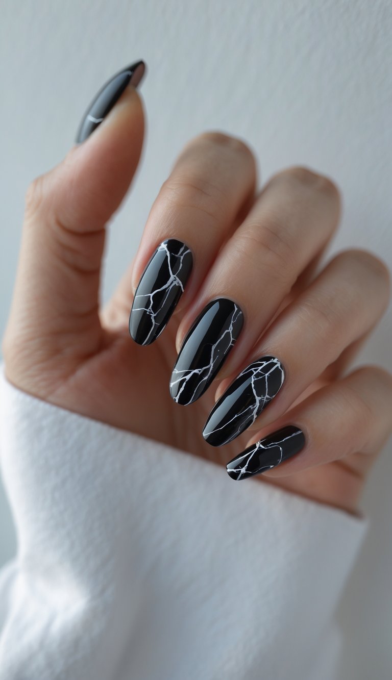 Close-up of a hand with black marble patterned nails on a white background.