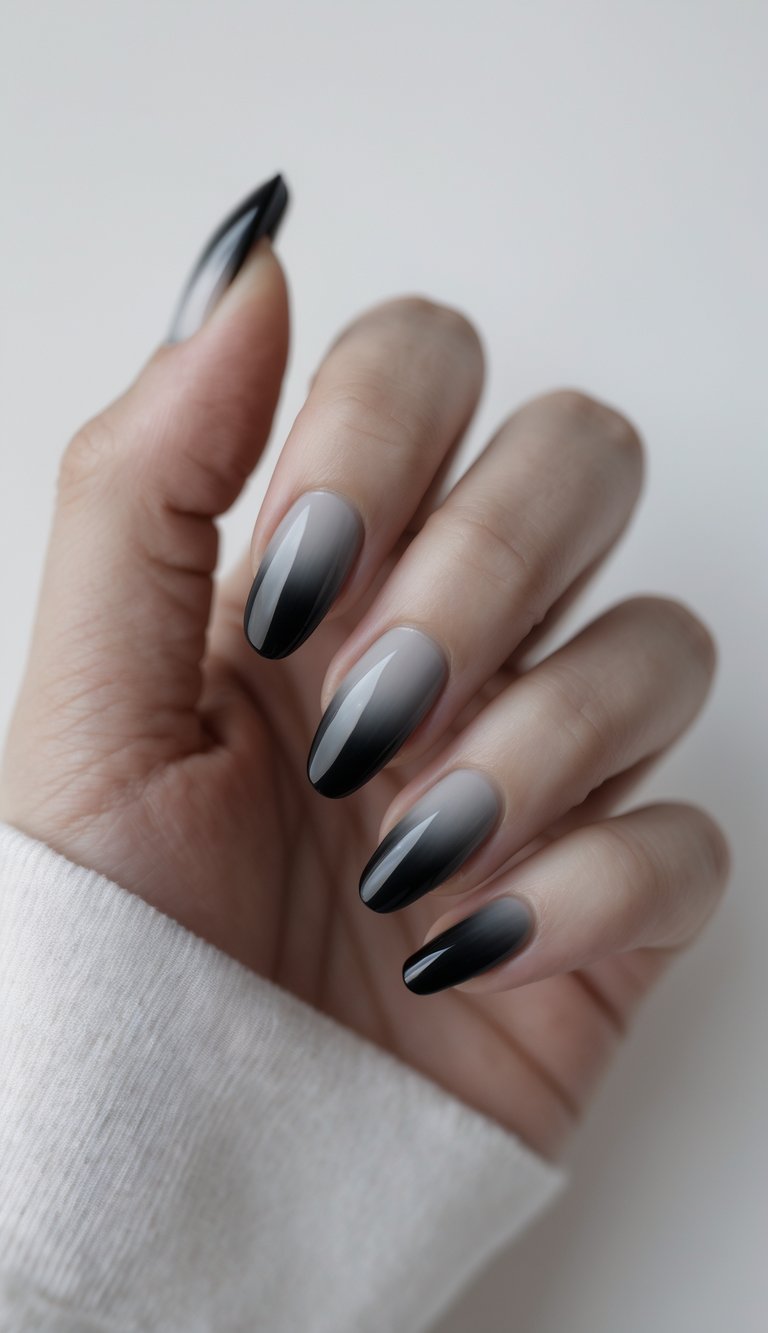 Close-up of one hand with dark gray to black ombre nails against a white background.