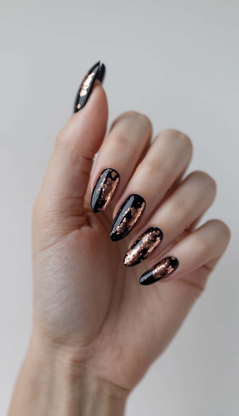 Close-up of one hand with black nails decorated with metallic rose gold flakes against a white background.