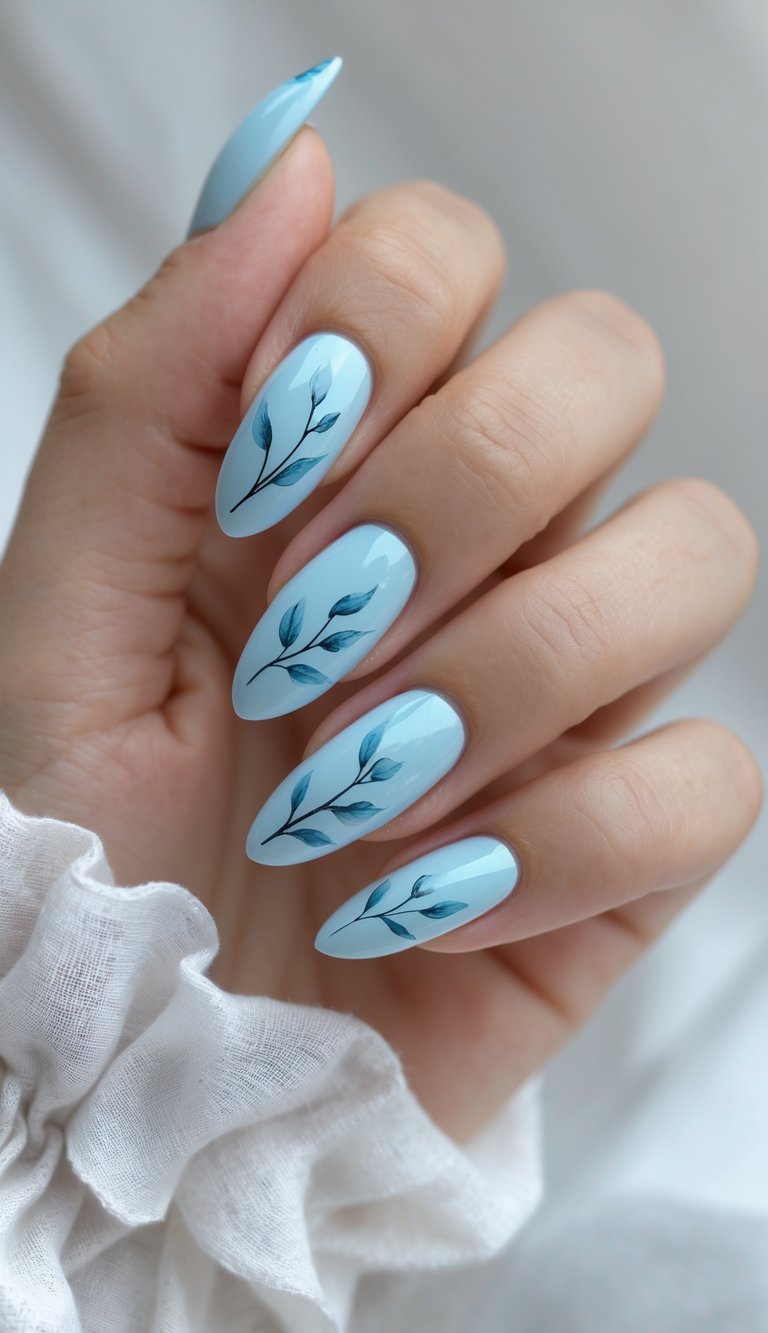 Close-up of a hand with pastel blue nails decorated with hand-painted leaves on a white background.
