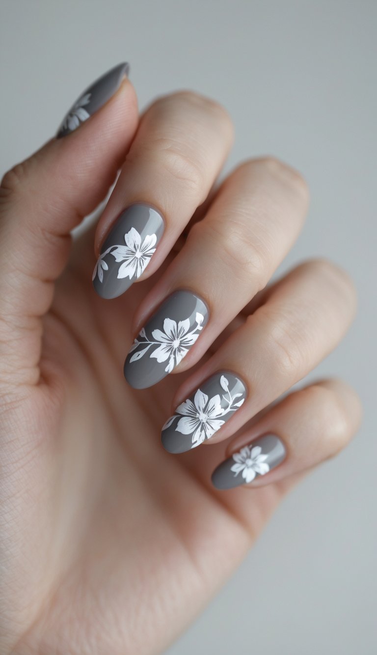 Close-up of one hand showing manicured nails with gray and white floral designs against a white background.