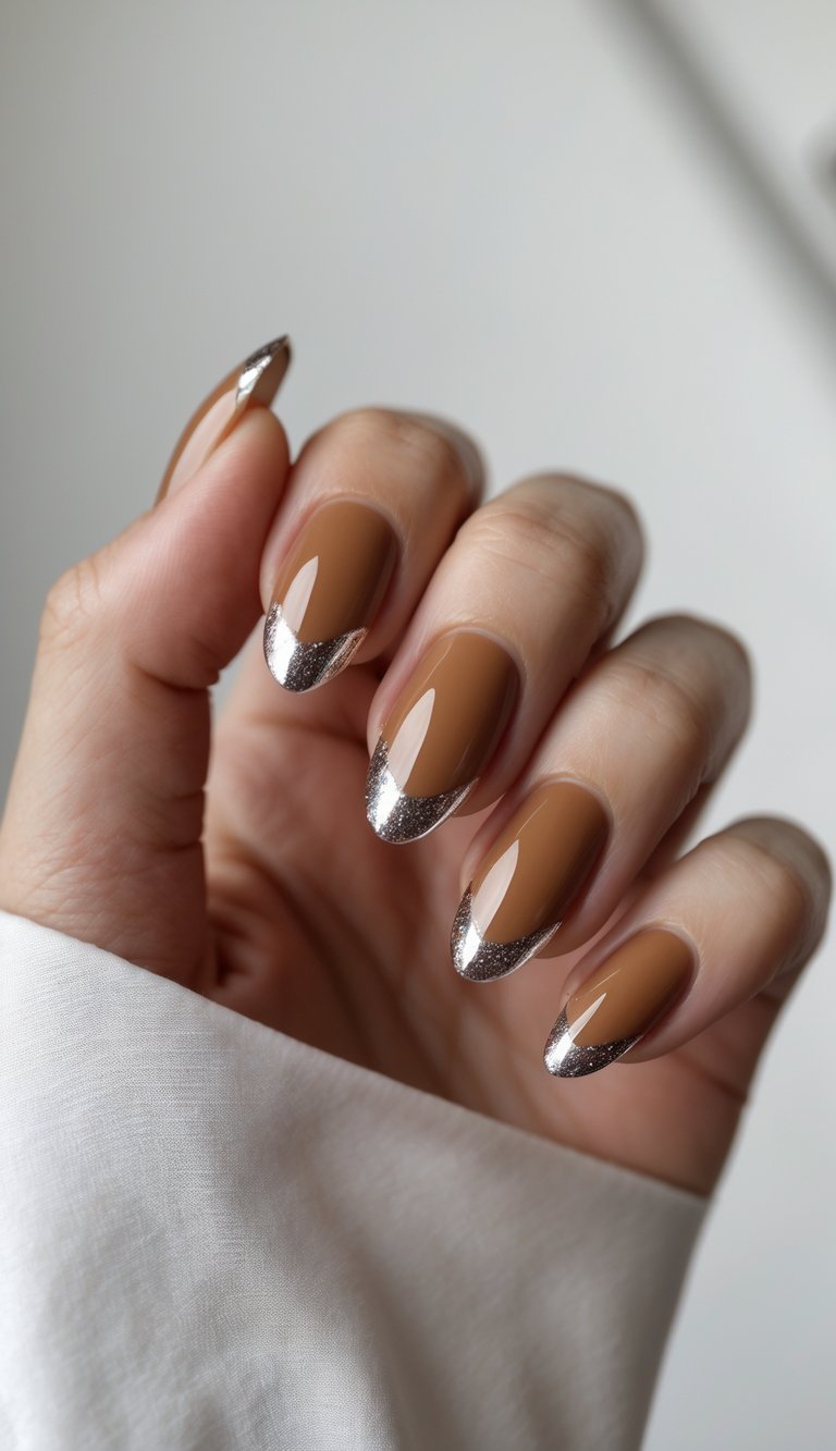 Close-up of one hand with matte caramel nails and shiny glossy tips against a white background.