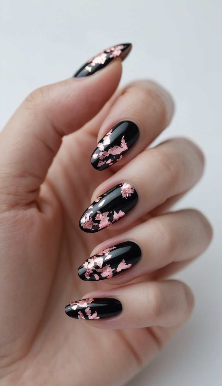 Close-up of one hand showing black nails decorated with pink foil flakes against a white background.