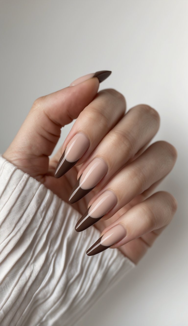 Close-up of one hand with neatly manicured nails featuring thin chocolate brown tips on a white background.