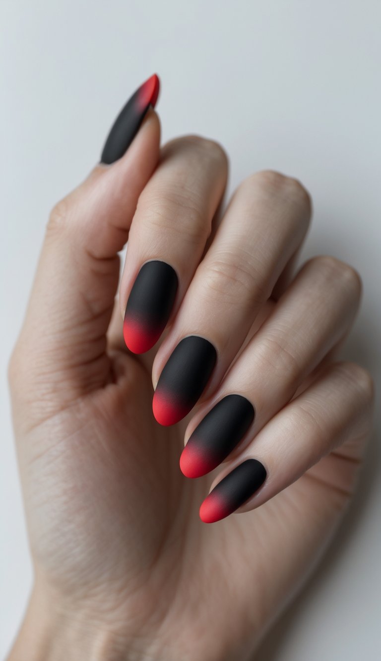 Close-up of one hand with matte black nails fading to red tips against a white background.
