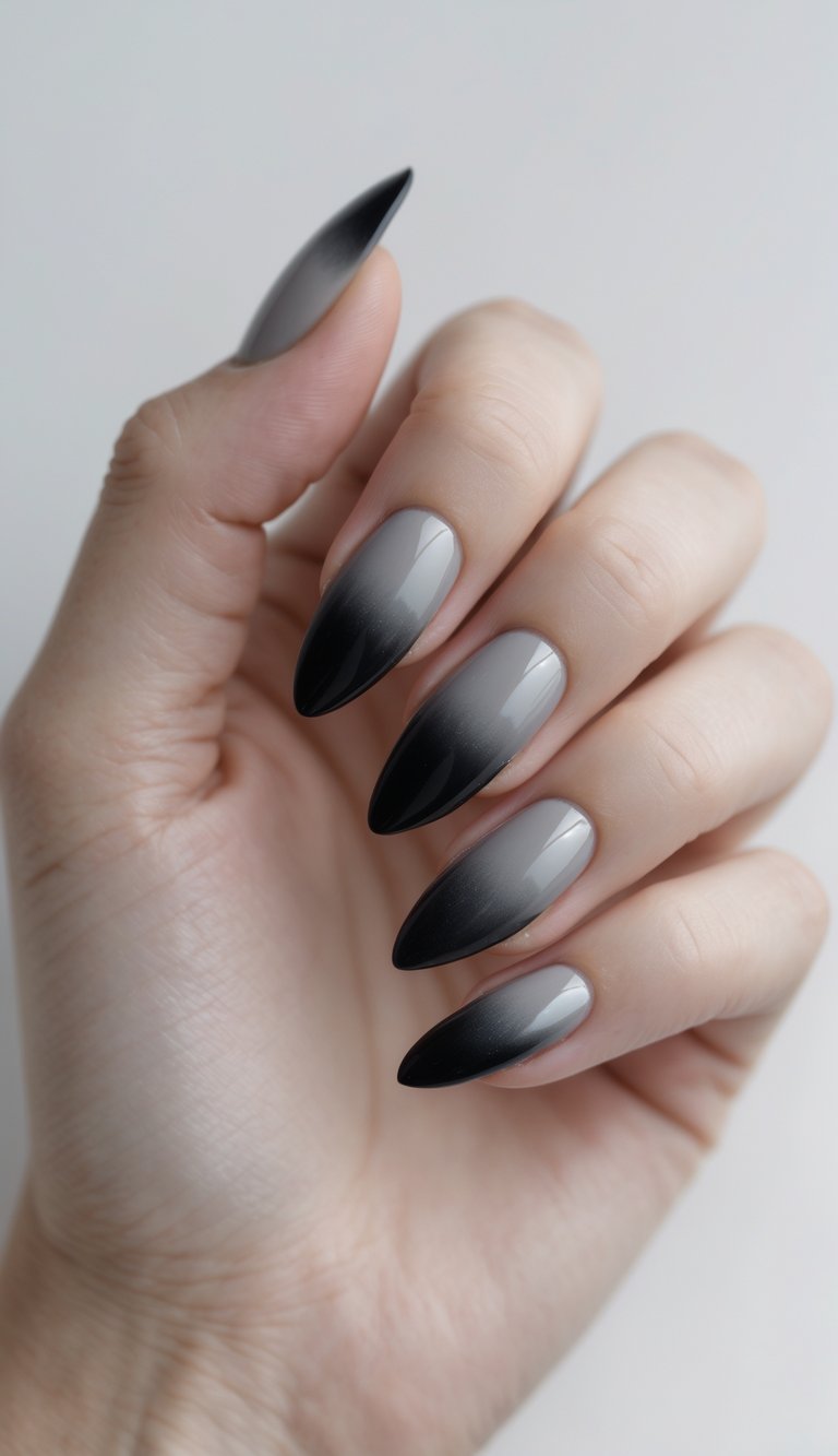 Close-up of one hand with black-to-gray smokey ombre nails against a white background.