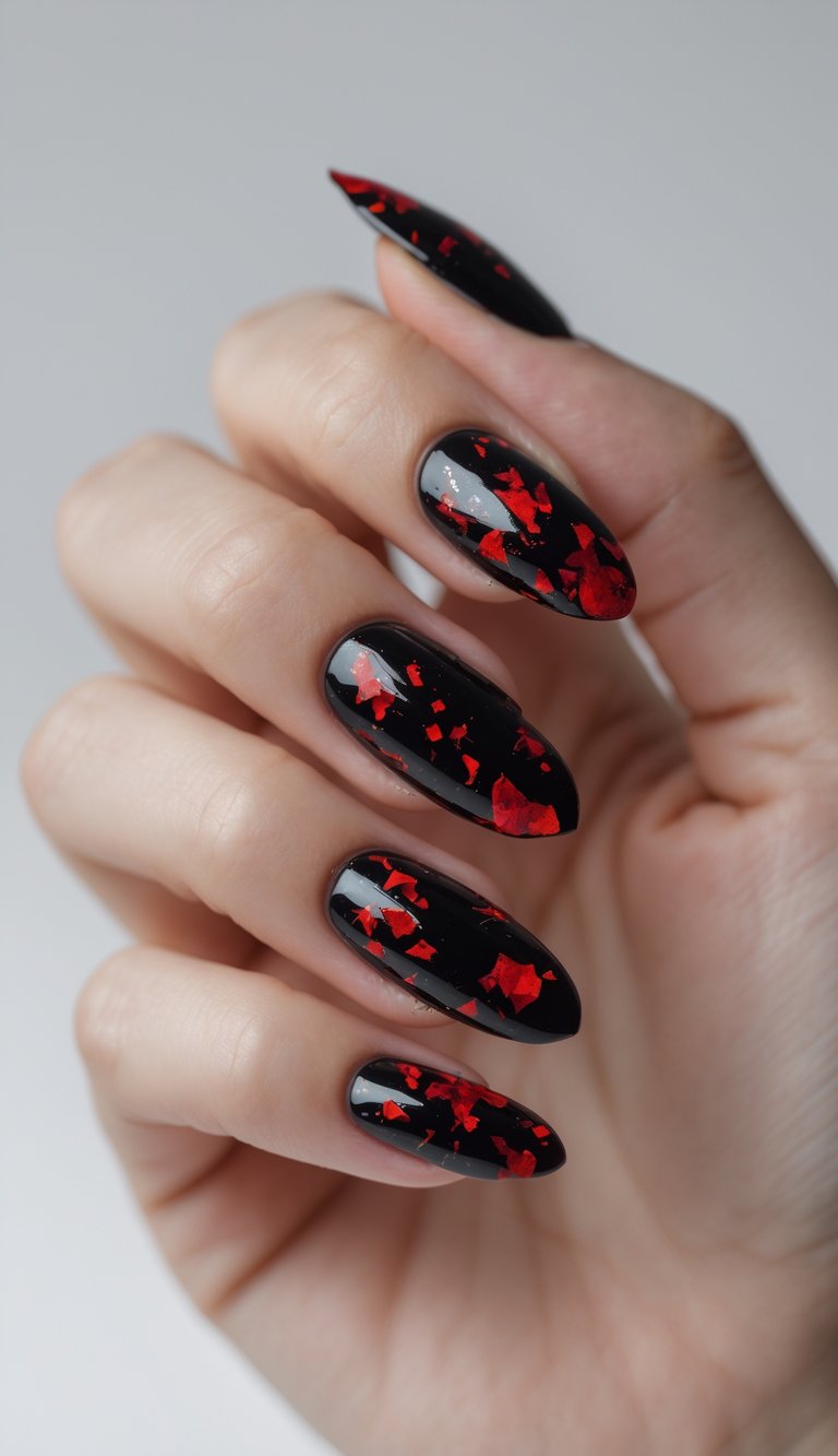 Close-up of one hand with black nails decorated with red flakes against a white background.