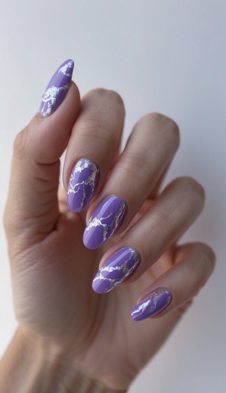 Close-up of one hand with purple nails featuring silver marble designs on a white background.