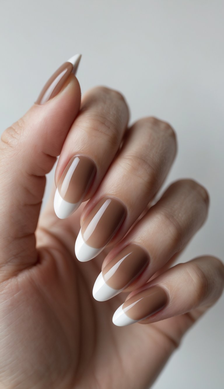Close-up of one hand showing nails with mocha-colored French tip manicure on a white background.