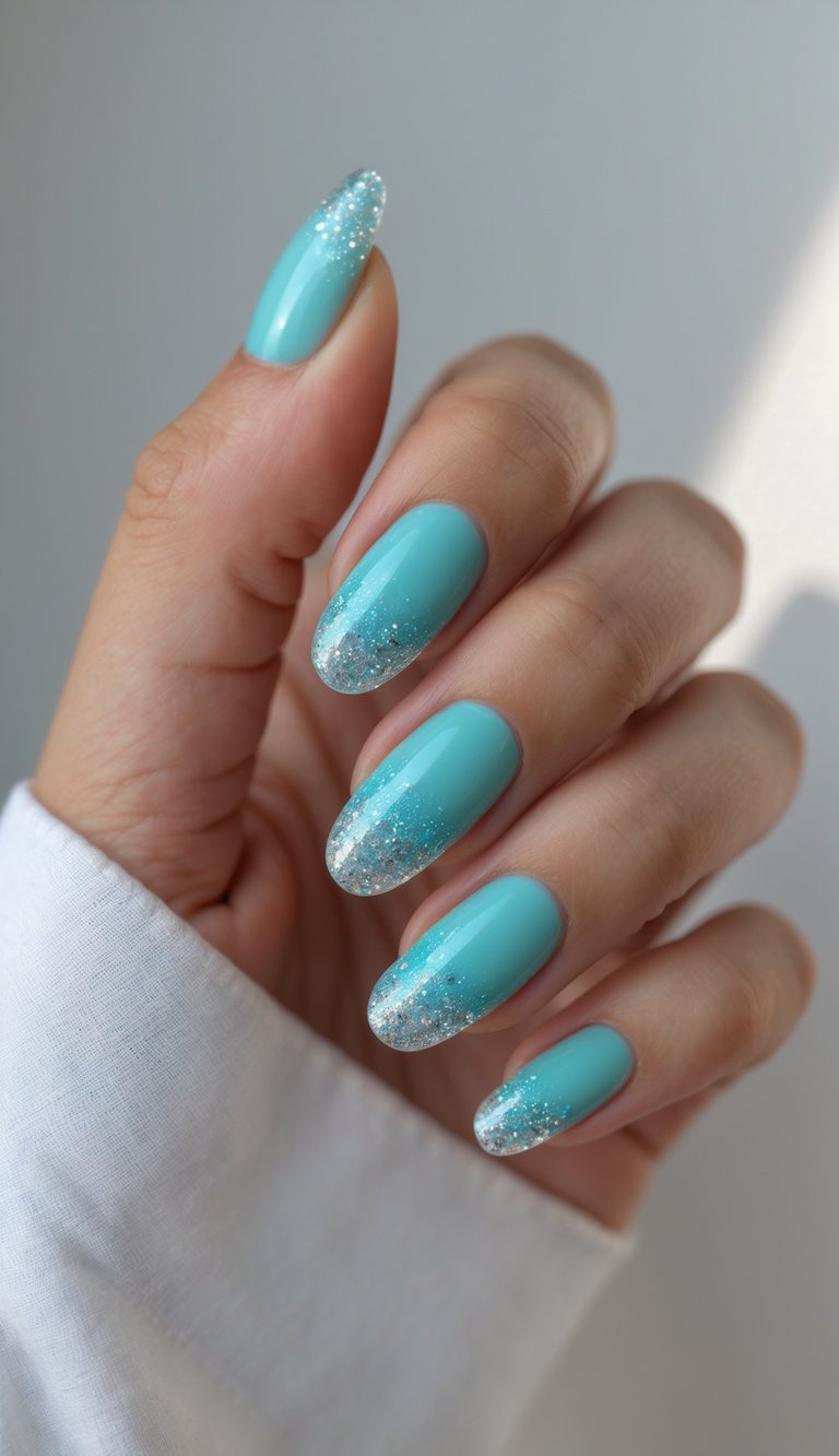 Close-up of one hand showing turquoise French pedicure with glitter tips on manicured nails against a white background.