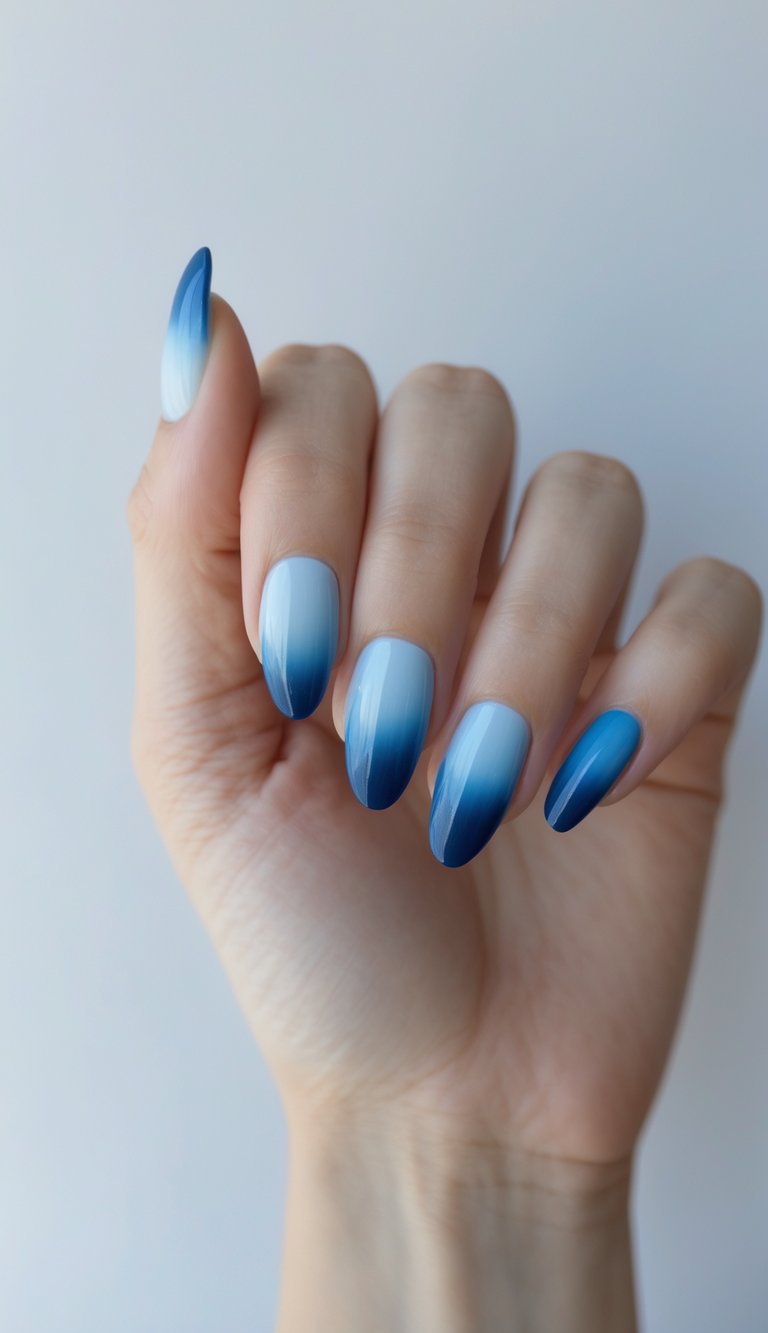 Close-up of one hand with neatly manicured nails showing a gradient from sky blue to navy blue on a white background.