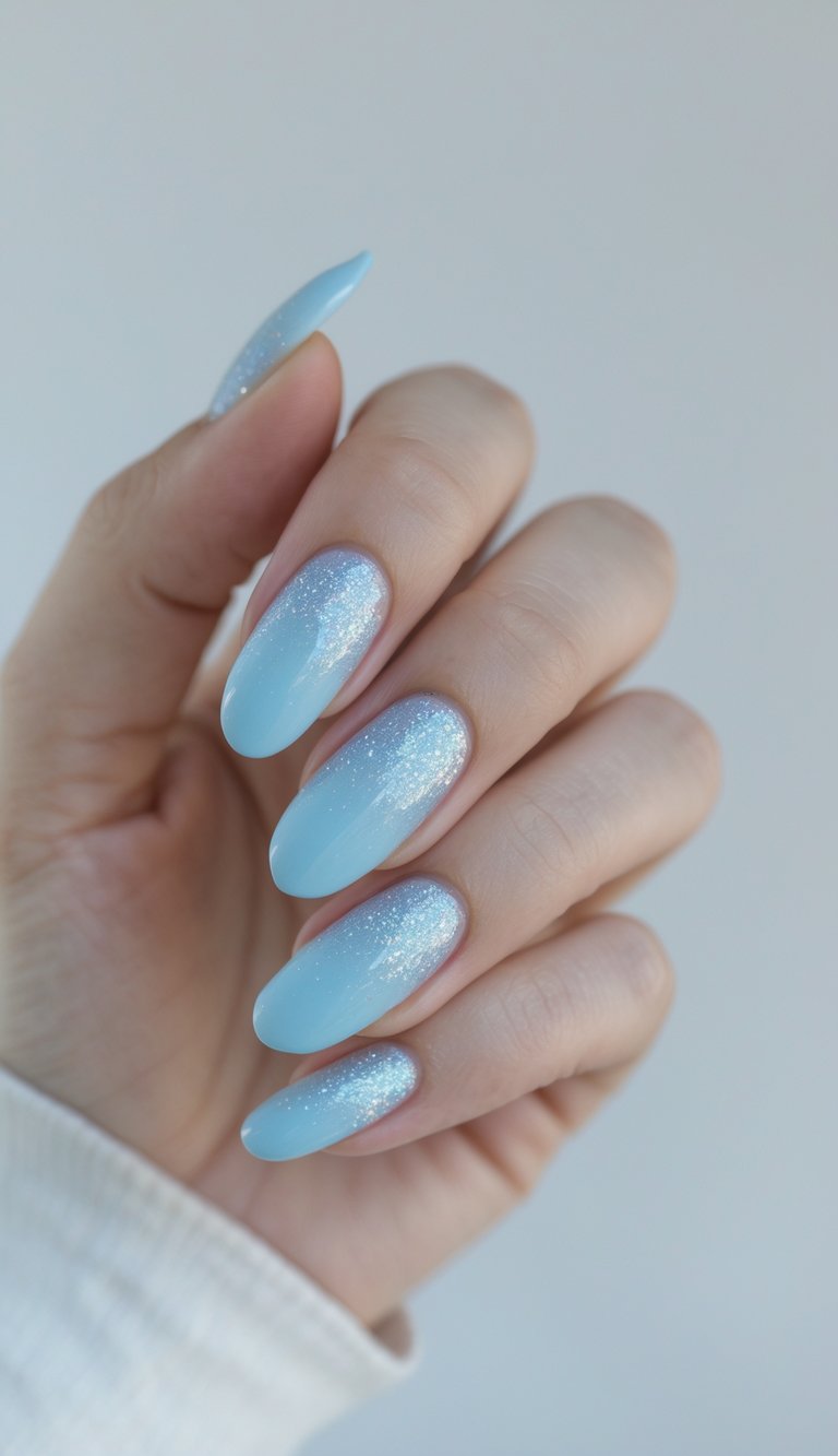 Close-up of one hand showing baby blue nails with a subtle glitter fade on a white background.