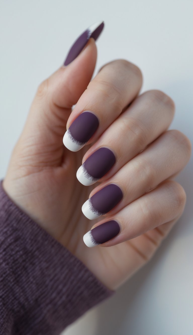 Close-up of one hand with plum French manicure nails against a white background.