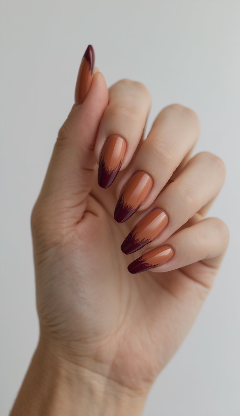 Close-up of one hand with terracotta nails and deep burgundy tips against a white background.