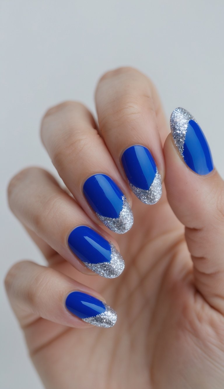 Close-up of one hand with royal blue nails and sparkly French tips against a white background.