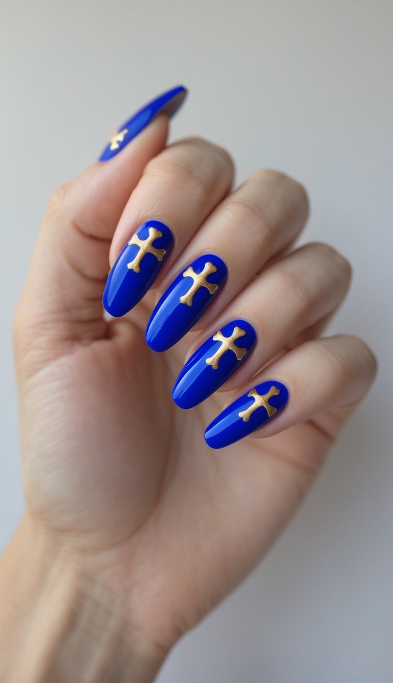 Close-up of one hand with royal blue nails featuring gold cross designs against a white background.