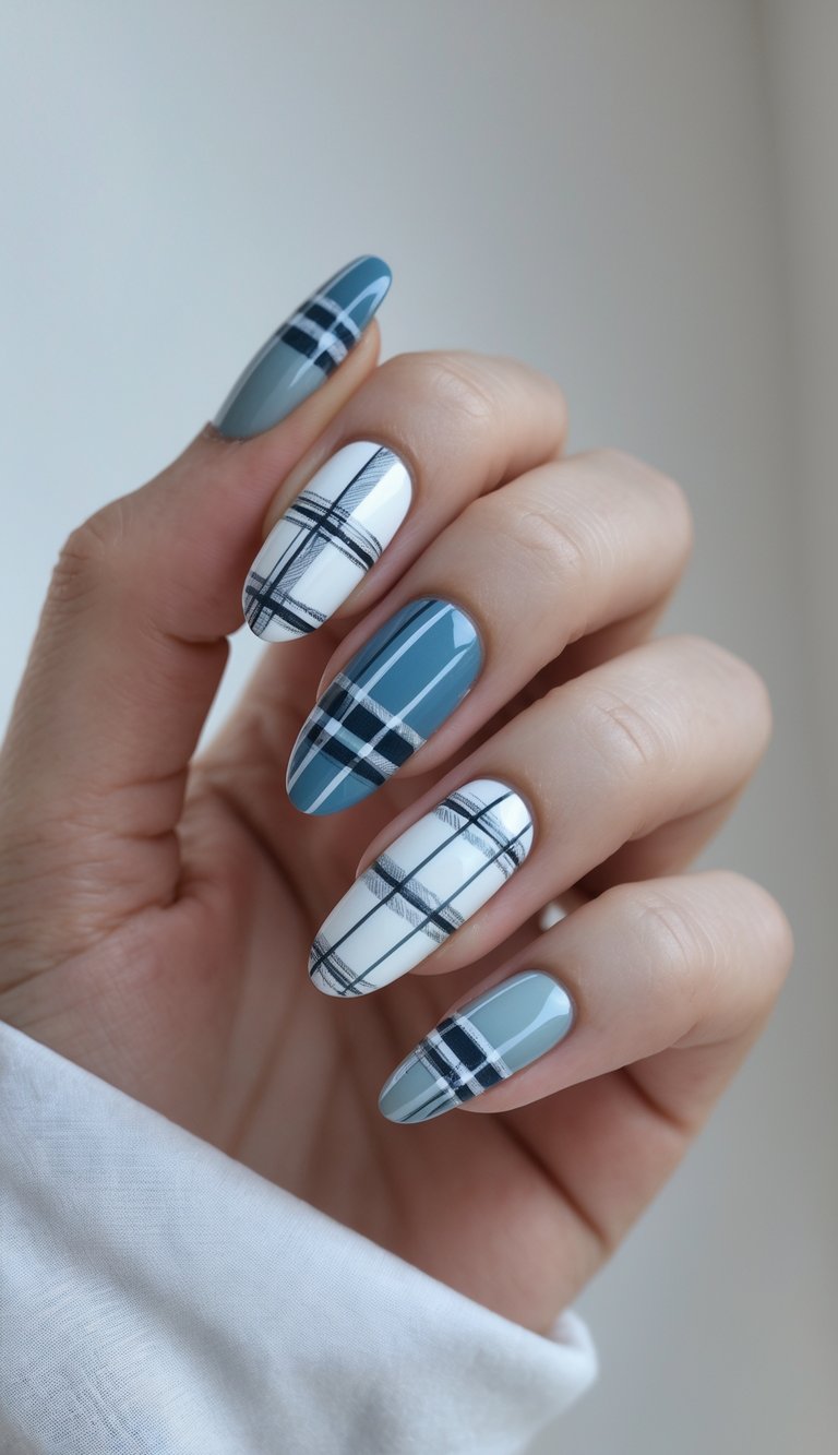 Close-up of one hand with nails painted in blue, white, and gray plaid patterns against a white background.