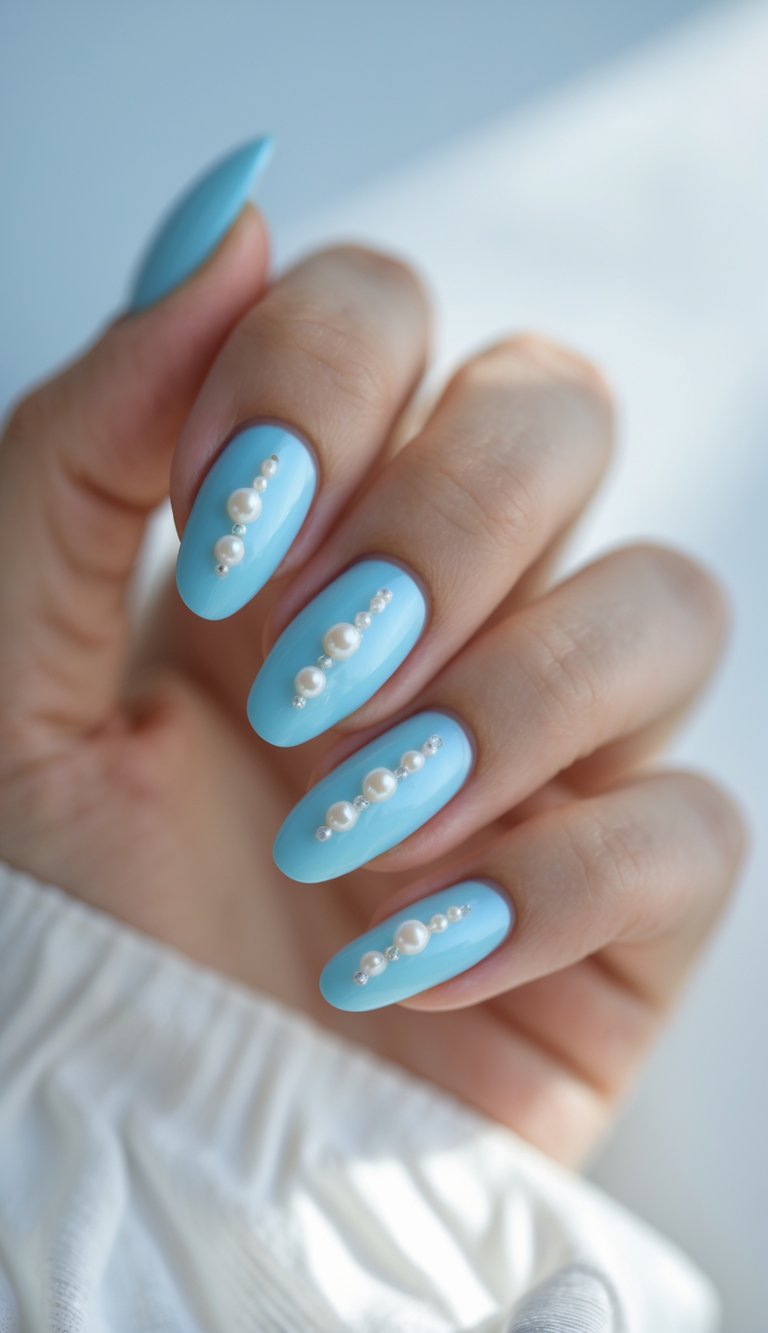 Close-up of one hand with baby blue nails decorated with small pearls on a white background.