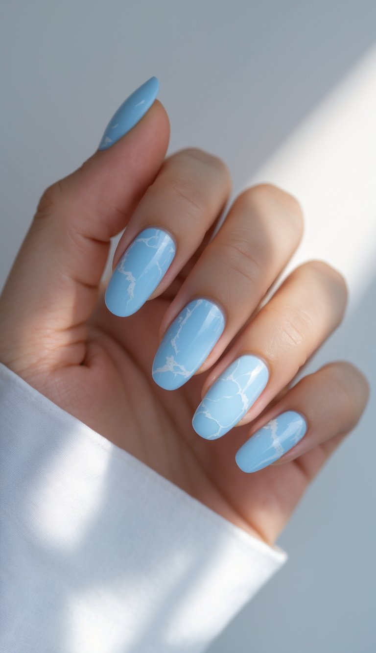 Close-up of one hand with sky blue nails featuring a white marbled pattern against a white background.