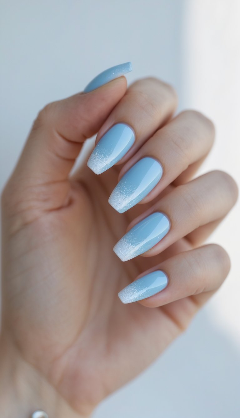 Close-up of one hand showing nails painted sky blue with white sparkling tips against a white background.