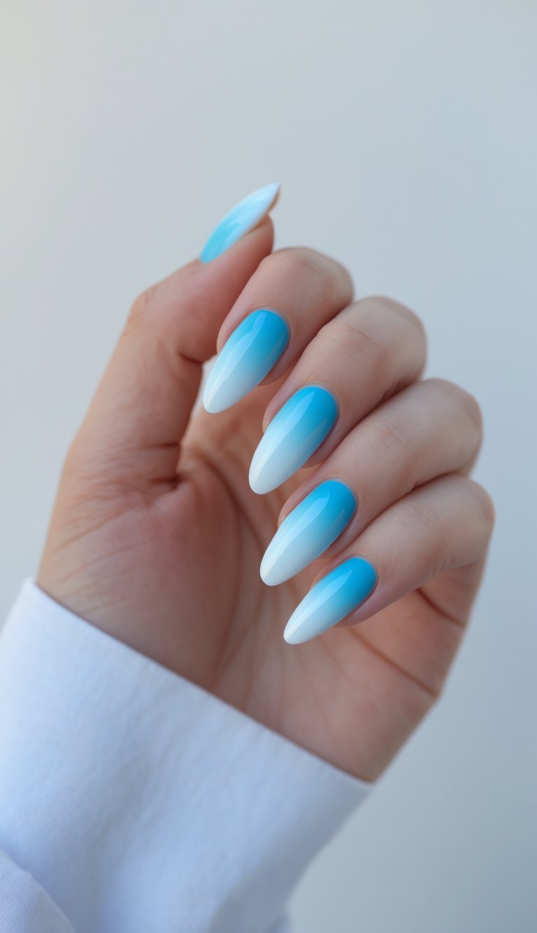 Close-up of one hand with sky blue to white ombre nail art on a white background.