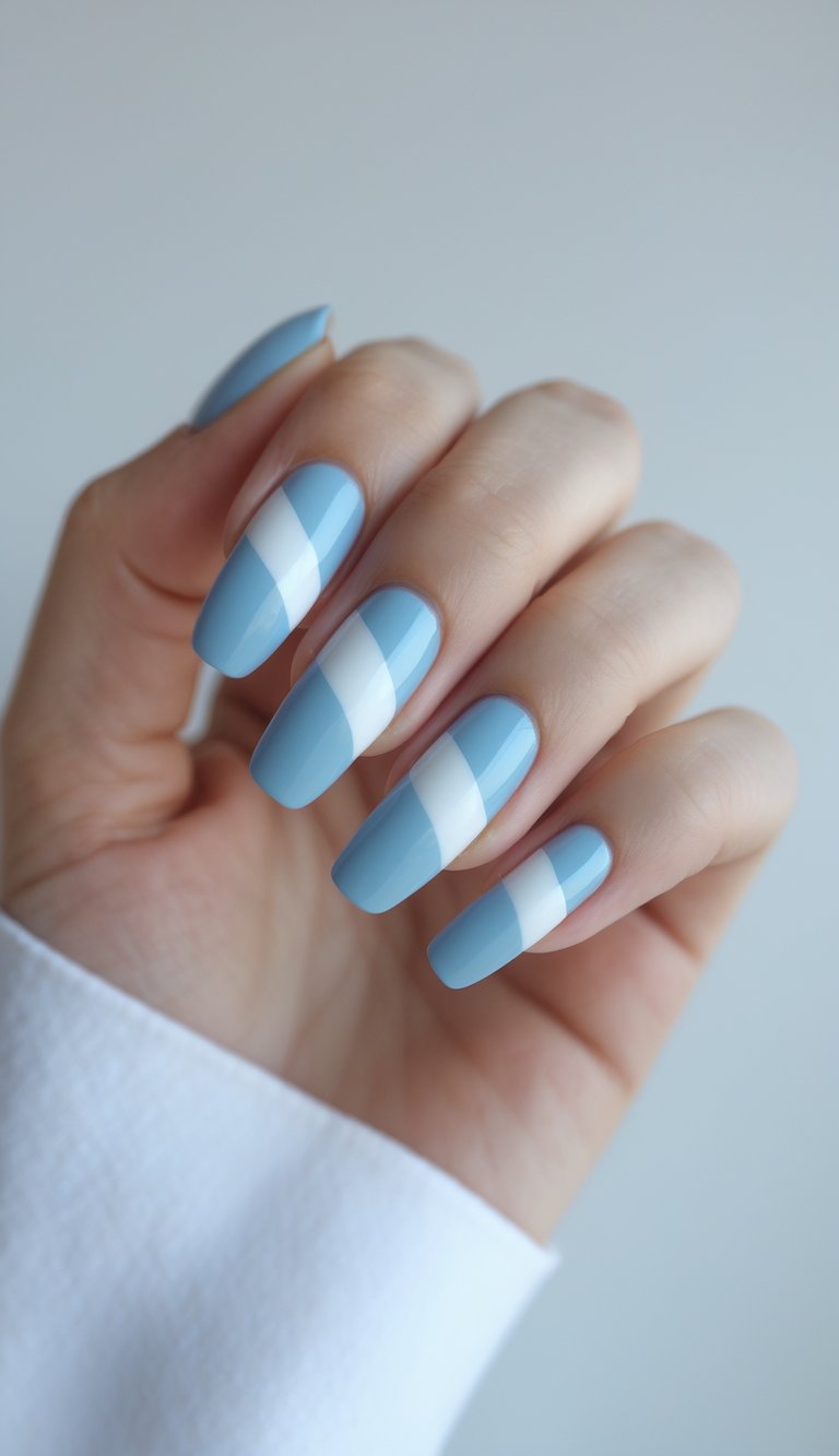 Close-up of a hand with sky blue nails featuring bold diagonal white stripes on a white background.
