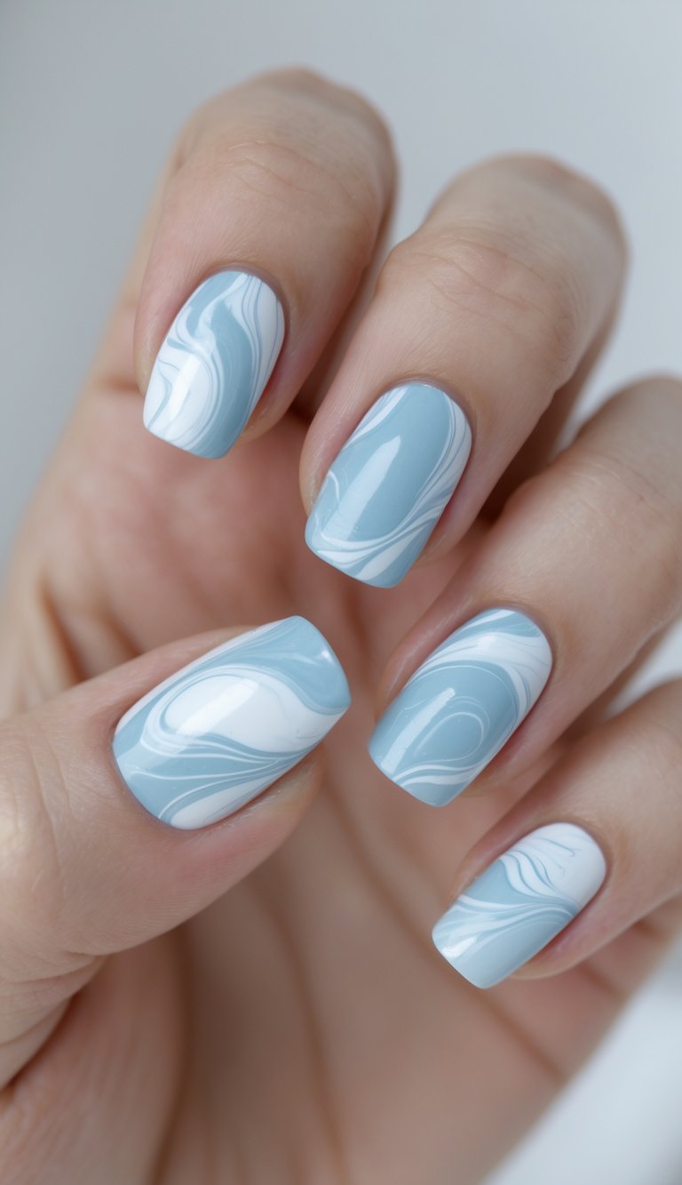 Close-up of one hand with nails painted in powder blue and white marble patterns against a white background.