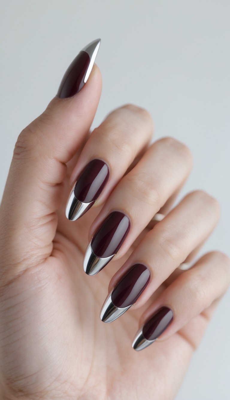 Close-up of one hand with wine-colored nails and metallic chrome tips against a white background.