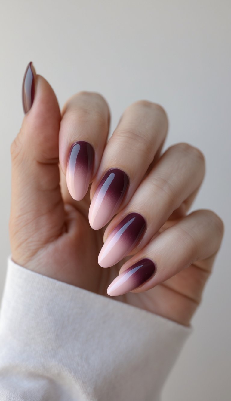 Close-up of one hand with neatly manicured nails painted in wine color with pink gradient accents against a white background.
