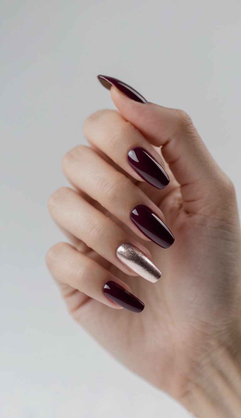Close-up of one hand with glossy deep wine colored nails and a metallic accent nail on the ring finger against a white background.