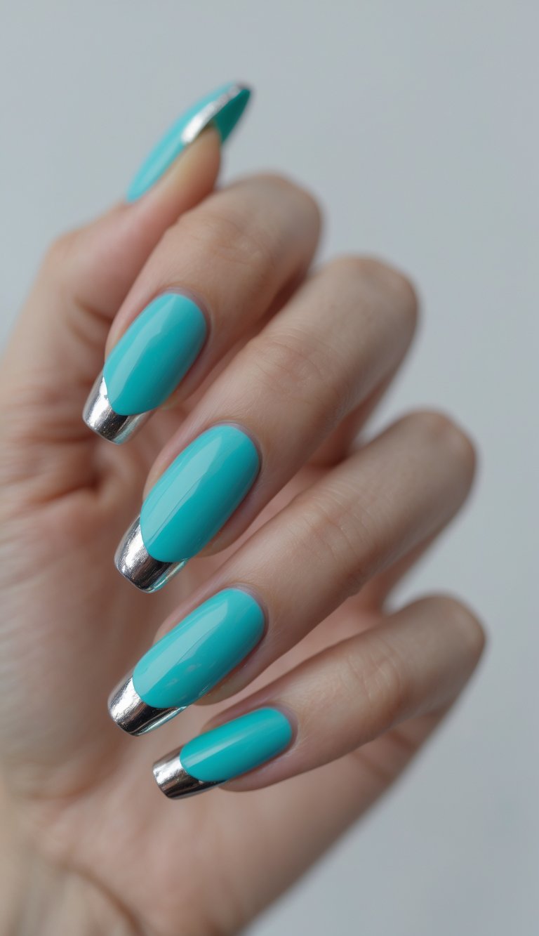 Close-up of one hand with turquoise French tip nails edged in metallic silver on a white background.