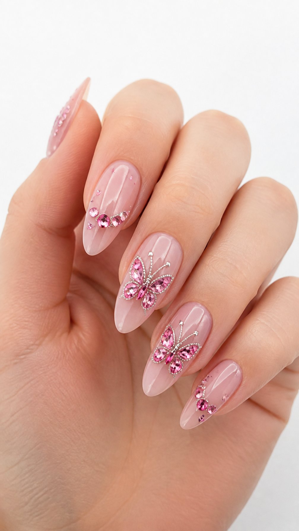 One hand with glossy pink nails decorated with sparkling rhinestone butterfly designs against a white background.