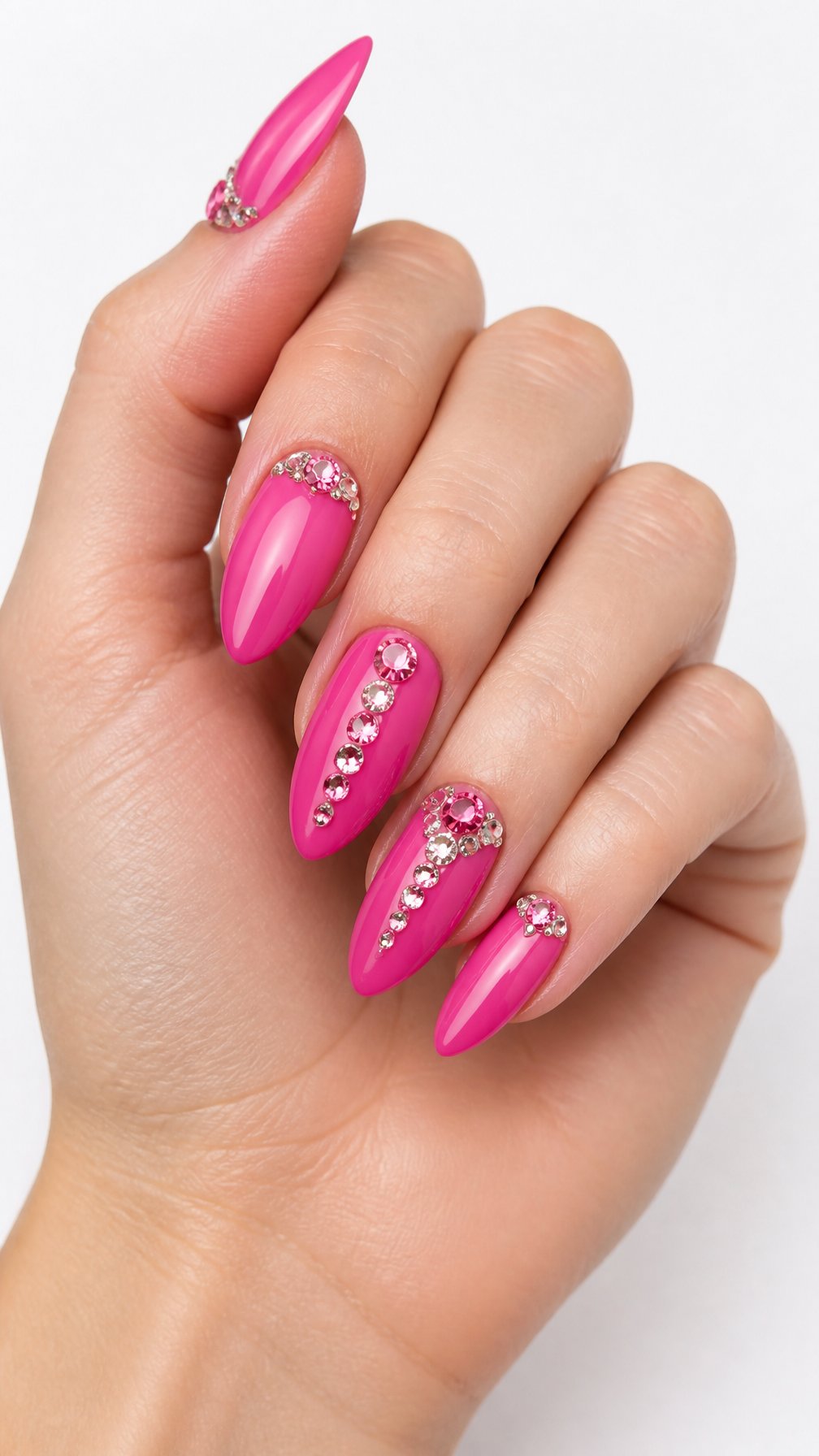 A single hand with glossy hot-pink nails decorated with sparkling rhinestones against a white background.