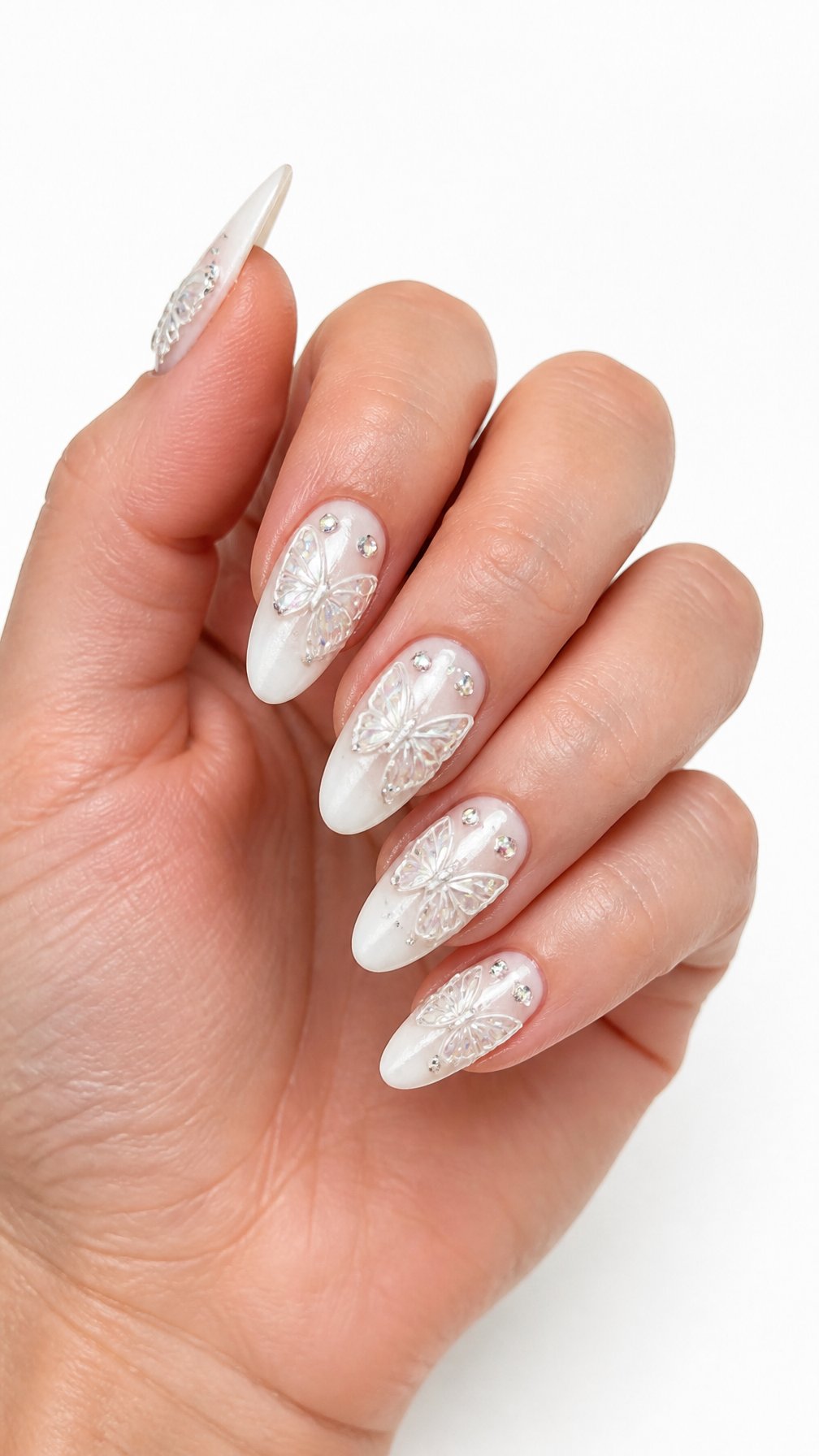A single hand displays glossy white butterfly nails decorated with sparkling rhinestones against a white background.