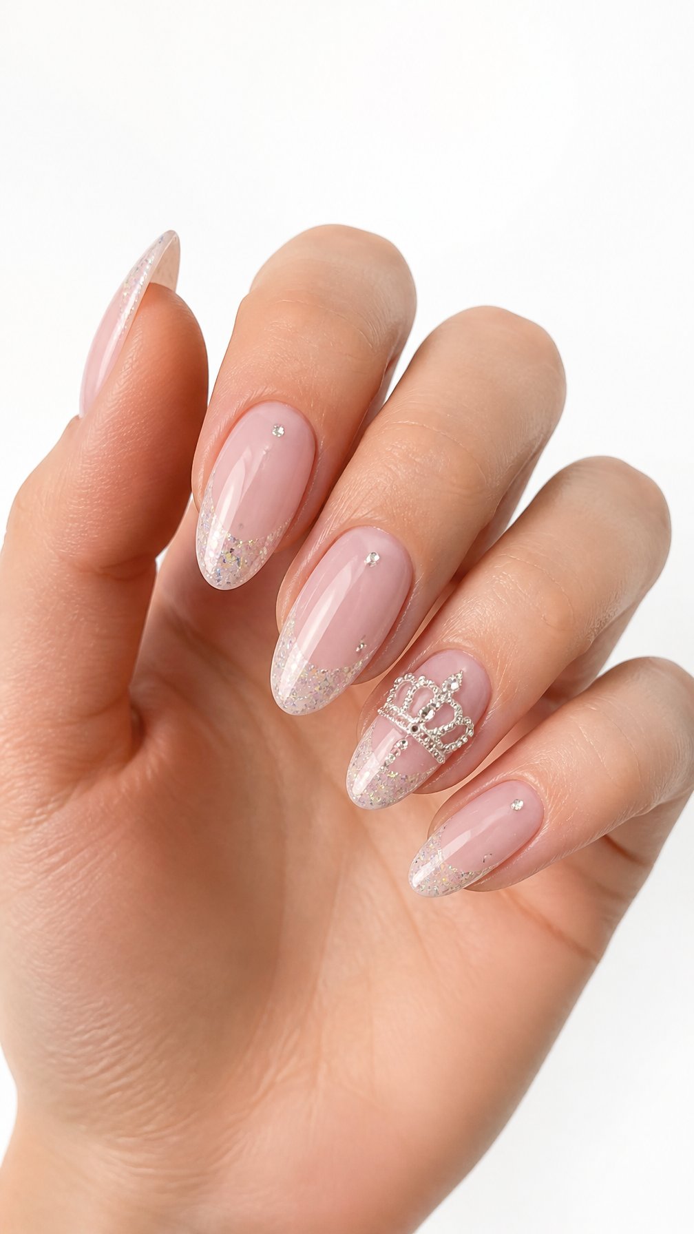 A single hand displays glossy pink almond-shaped nails with one rhinestone crown accent nail against a white background.